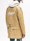 Coat styled with cream hoodie. Back angle view of Elongated Cold War Work Jacket in Camel.