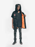 Candid shot of Half-Sleeve Military Parka in Black on model, showcasing inner orange lining and hoodie