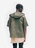 Back view of Short-Sleeve Asymmetrical Hooded Parka in Olive on model, layered with Basic Raw-Cut Elongated Short Sleeve Tee in Sand